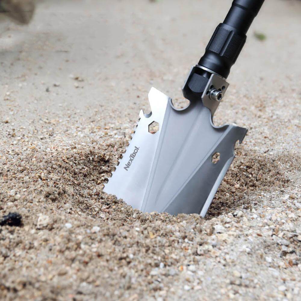 The multi-tool shovel being used to dig up sand.