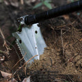 The multi-tool shovel head being used at a 90 degree angle to dig out dirt.