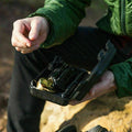 Someone holding the opened outdoor emergency survival kit portable travel case which contains the included items.