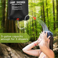 A woman outside in a forest using the portable camping shower solar heated bag which has a 5 gallon capacity.