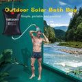 A man outside using the portable camping shower solar heated bag. A river and forest in the background.