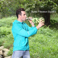 A man outdoors using the water purification straw and the bottle filtration system.